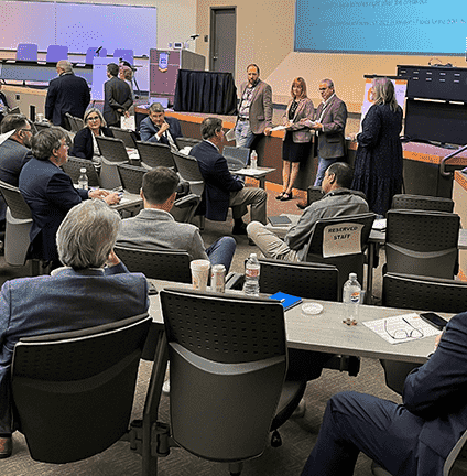 <img src=_blog-box-ideation-11-2023.html alt="a group of people sitting listening to three people standing in front talk"?